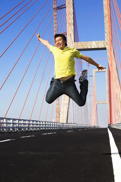 Молодой человек прыгает очень высоко в районе моста — стоковое фото