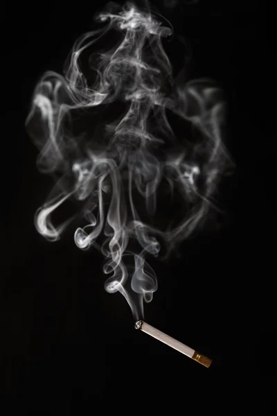 Горящая сигарета, падающая с дымом, абстрактной формы — стоковое фото