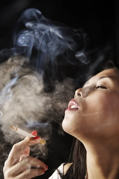 Женщина вдыхает дым от сигареты — стоковое фото