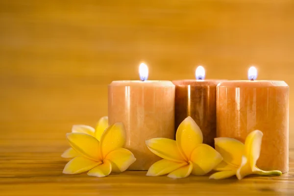 Aromatic candles with frangipani on bamboo mat — Stock Photo, Image