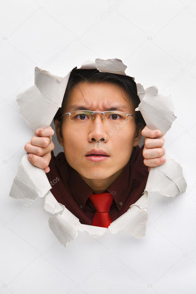 Man gazing seriously from hole in wall