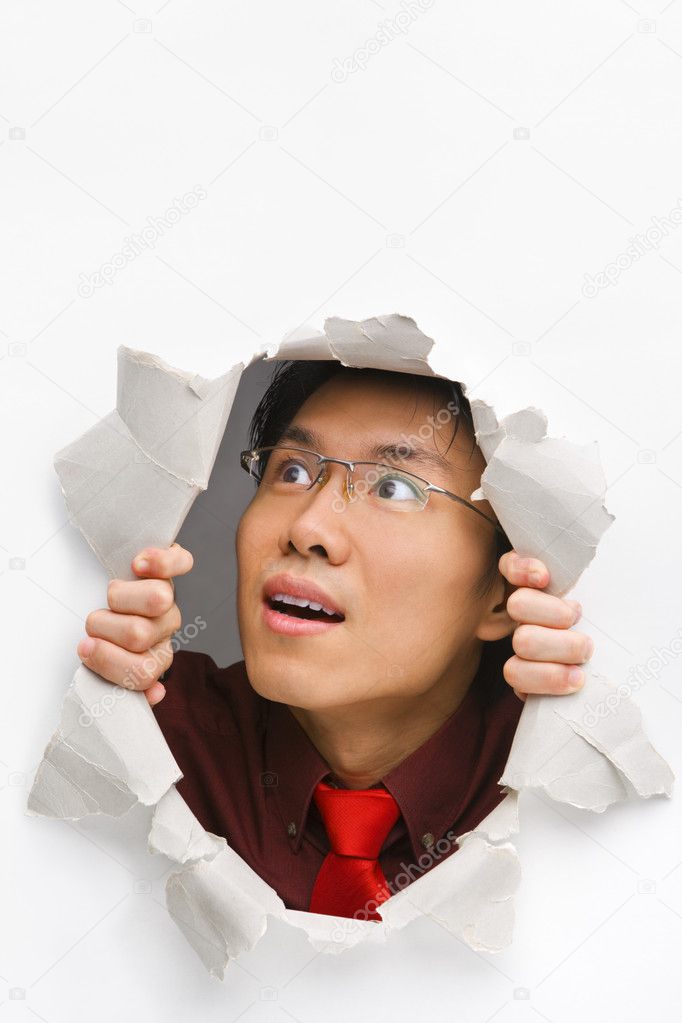 Man looking up happily from hole in wall