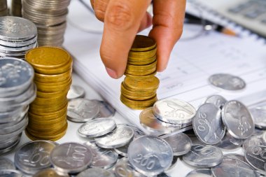 Hand put coins in stack on the book clipart