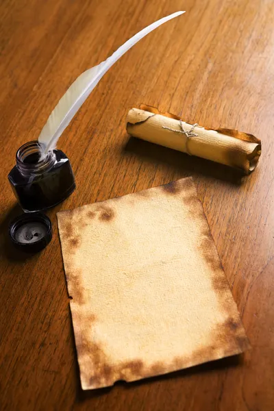 Papel viejo, pluma de pluma y pergamino sobre mesa de madera — Foto de Stock