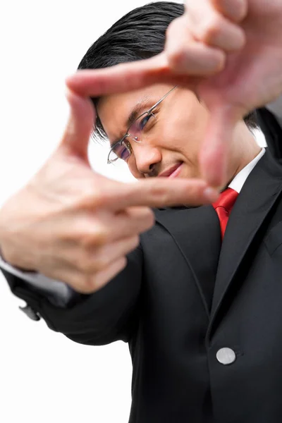 Азиатский бизнесмен смотрит на свою перспективу, подставляя пальцы — стоковое фото