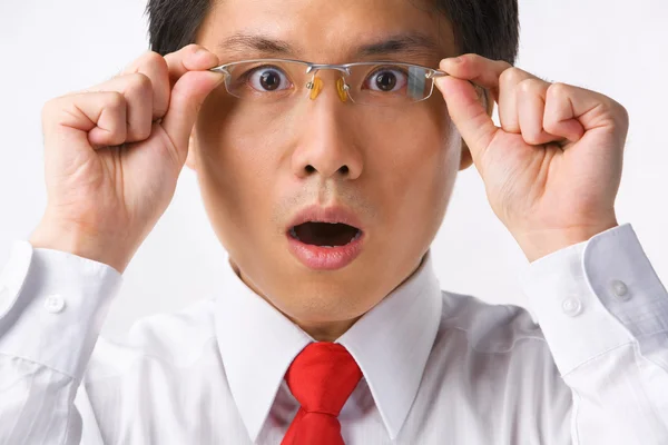 Asian businessman surprised holding glasses to camera — Stock Photo, Image