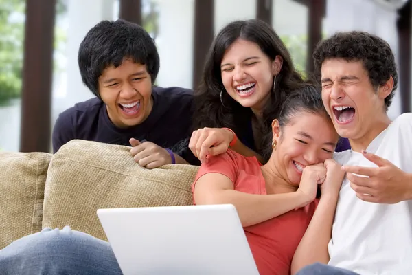 Multi etnické studenti smát něco na laptop — Stock fotografie