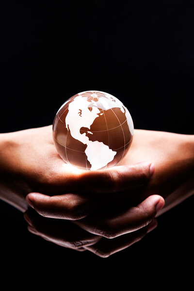 Both hands holding a glass globe on it showing America continent