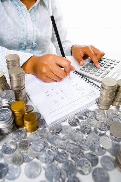 Mujer trabajando en contabilidad con muchas monedas alrededor — Foto de Stock