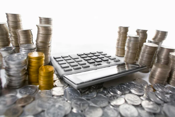 Calculator between pile of coins — Stock Photo, Image