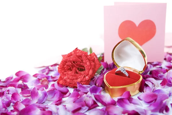 Ring, rose and valentine card on rose petals — Stock Photo, Image