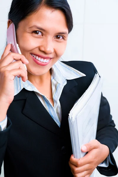 Young businesswoman smiling to camera while listening to her cel — Stockfoto
