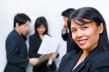 Young Asian Businesswoman smiling to camera with other bu clipart