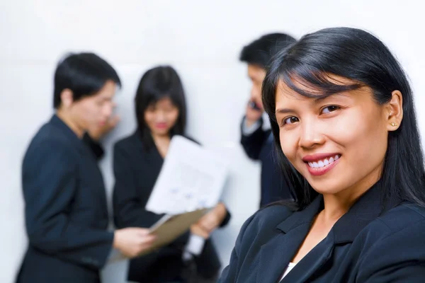 Jonge Aziatische zakenvrouw glimlachen naar camera met andere bu — Stockfoto