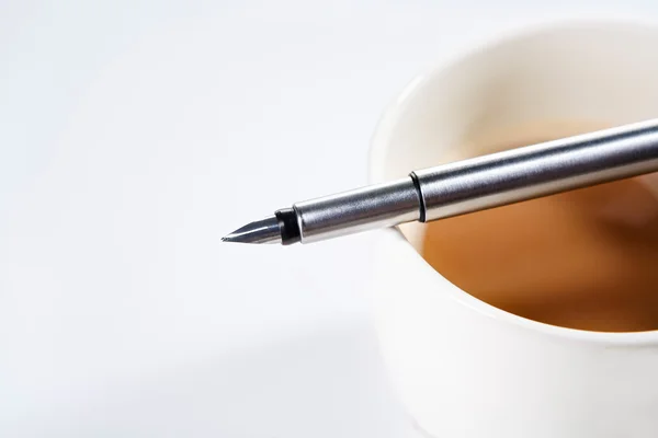 Caneta-tinteiro sobre xícara de café — Fotografia de Stock