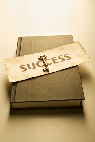 Book with golden key and success label (warm) — Stock Photo, Image