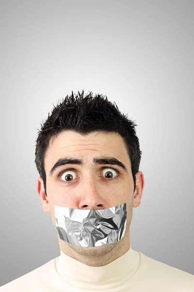 Scared young man having gray duct tape on his mouth — Stock Photo, Image