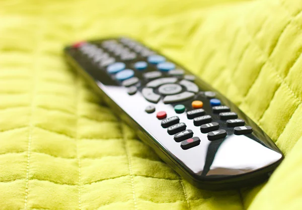 Black remote control on a green blanket — Stock Photo, Image