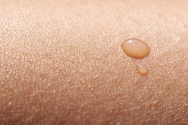 Macro of water drop on female skin clipart