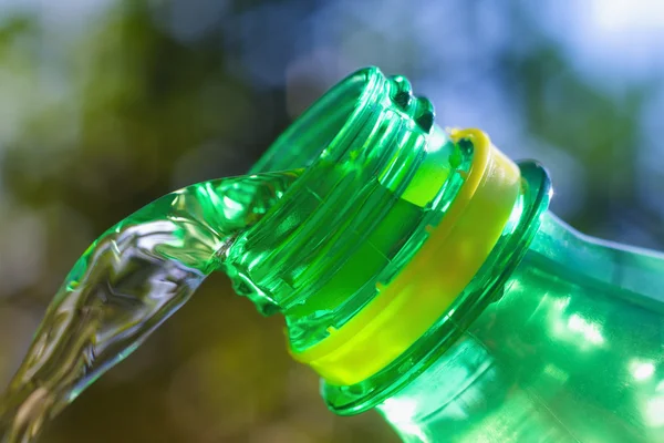 Primer plano del agua que fluye de la botella verde — Foto de Stock