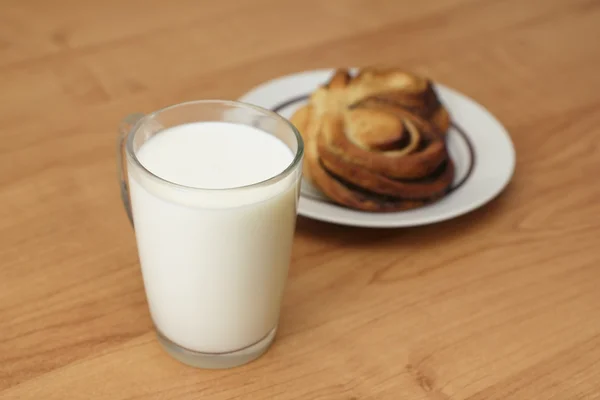 Una taza de leche y bollo de canela — Foto de Stock