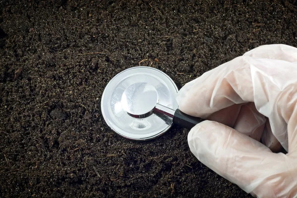 stock image Black soil and stethoscope concept of world without pollution