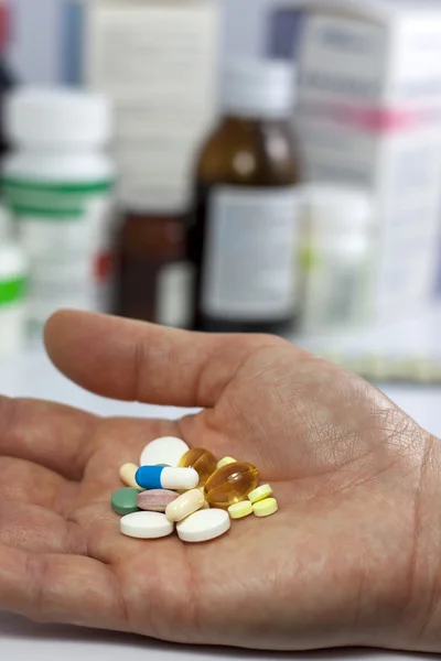 Таблетки в руке против аптеки — стоковое фото