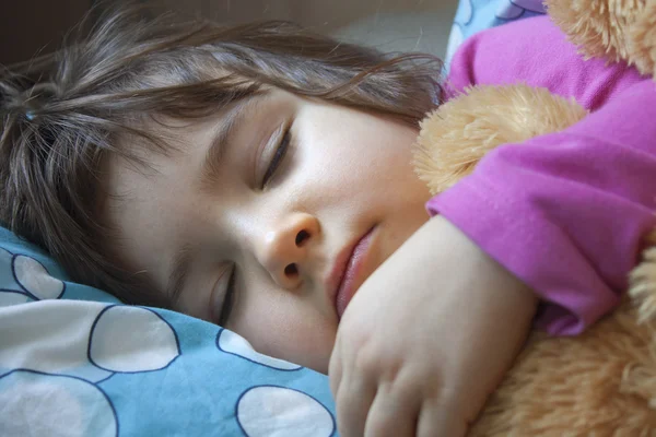 Sleeping child in her bed with teddy bear — Stock Photo, Image