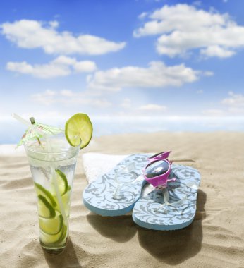 Sunglasses drink in sand on beach at sea holiday concept clipart