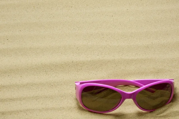 Sunglasses on beach in sand holiday background concept — Stock Photo, Image