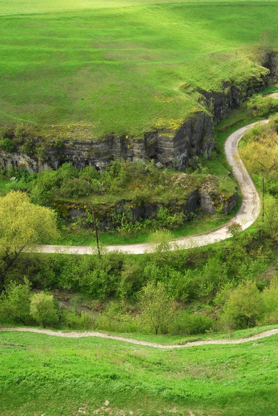 stock image The road in the green hills and stone cliffs