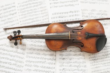An old violin with a bow on the background music clipart