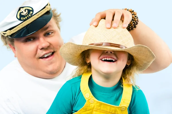 Hombre poniendo sombrero en la cabeza de su hija mientras ella se ríe — Foto de Stock