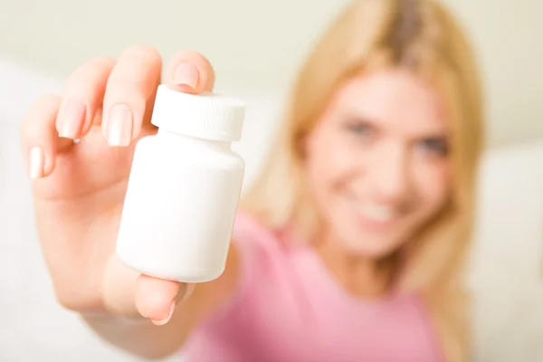 La mano de la hembra sosteniendo botella de plástico píldora que contiene vitaminas — Foto de Stock
