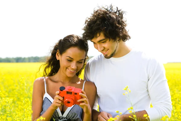 Happy guy looking at photo camera in girl's hands standing nearby — Stock Photo, Image