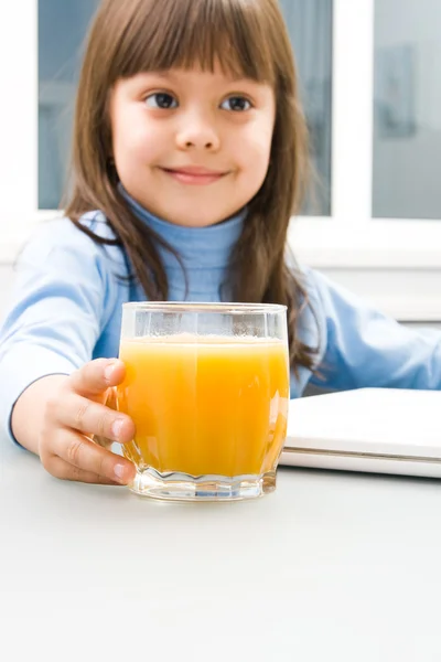 Positive childs hand touching a glass of orange juice — Stock Photo, Image
