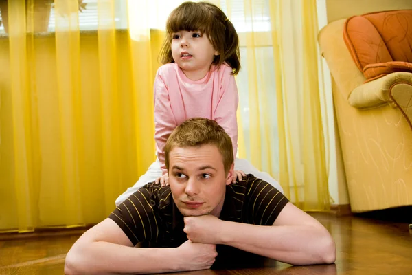 Glückliche Tochter, die auf dem Rücken ihres Vaters sitzt und beide zur Seite schauen — Stockfoto