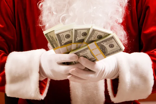 Santa händer med travar av dollar sedlar — Stockfoto