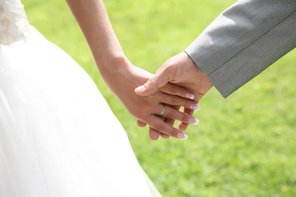 Bruiden hand met die van haar echtgenoot op groene achtergrond — Stockfoto