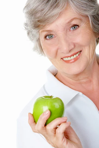 Senior woman holding an apple and eating it — Stock Photo, Image