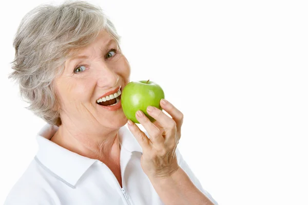 Старшая женщина держит яблоко у рта — стоковое фото