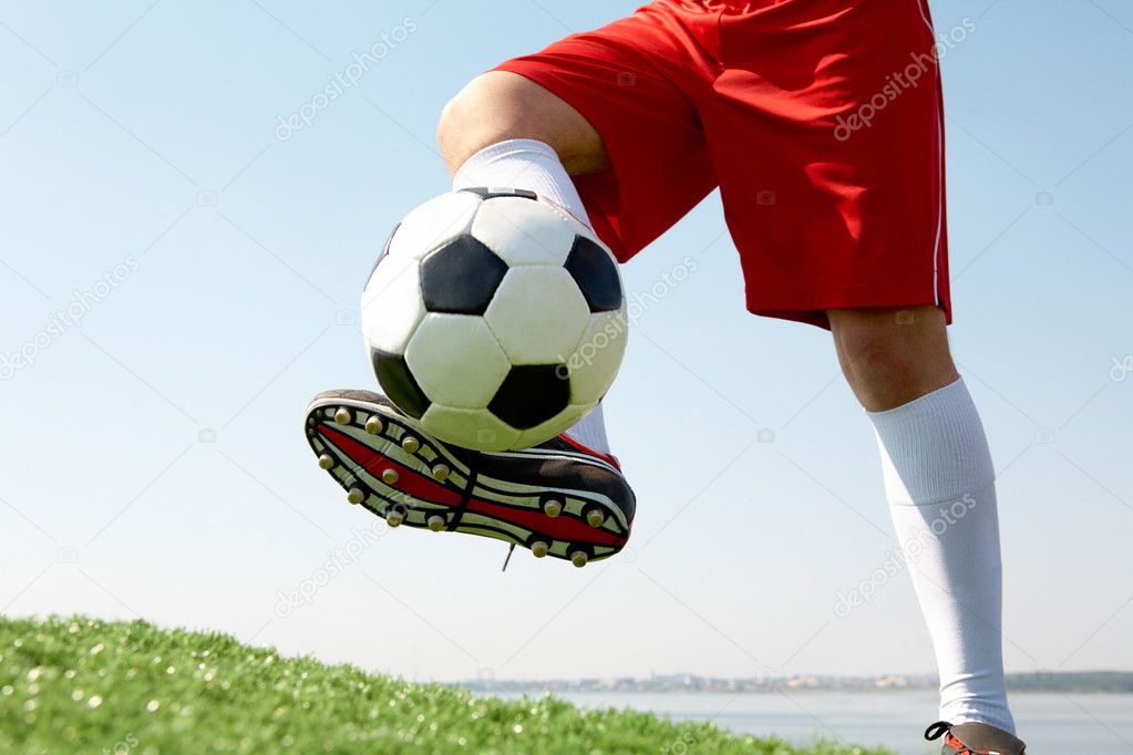 Horizontal image of soccer ball being kicked by footballer against