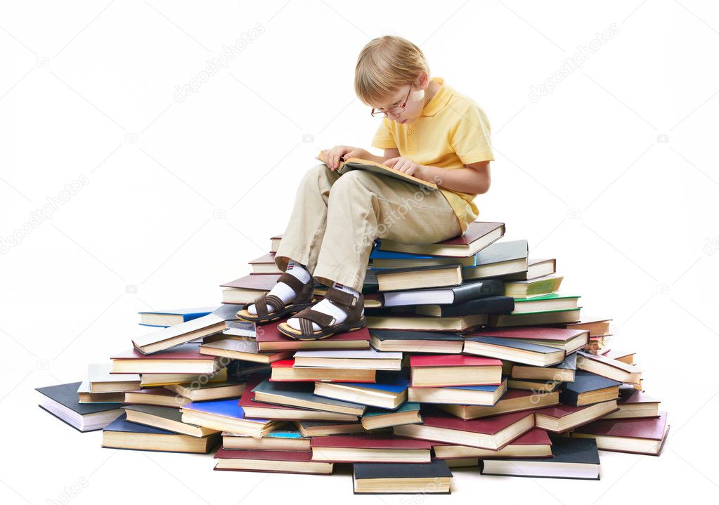 Portrait of diligent pupil sitting on top of books and reading