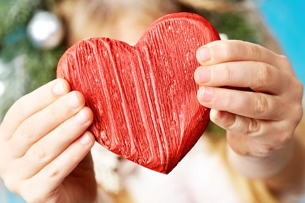 Primer plano del corazón rojo de madera en las manos del niño que lo muestra —  Fotos de Stock
