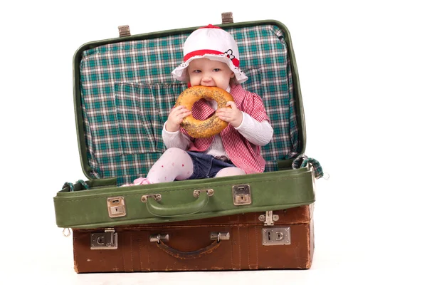 Little girl in the suitcase eating bread — Stock Photo, Image