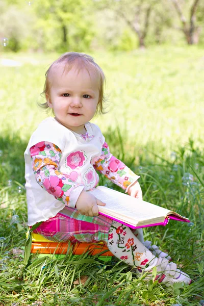 Lilla barnet läsa bok i parken — Stockfoto