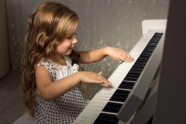 Blond girl playing a piano clipart