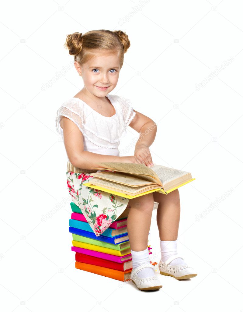Little girl sitting on stack of books and reading a book