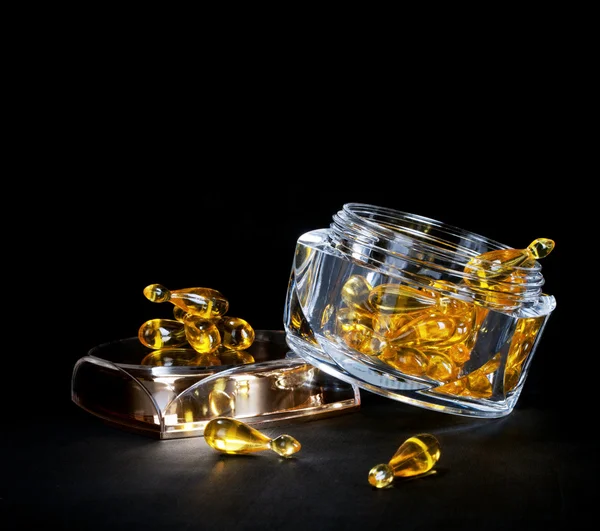 Kosmetyki starzenie - kapsułki żelem leczenie w szklanych można na czarnym tle — Zdjęcie stockowe