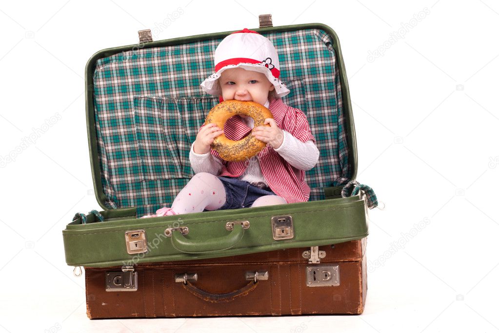 Little girl in the suitcase eating bread